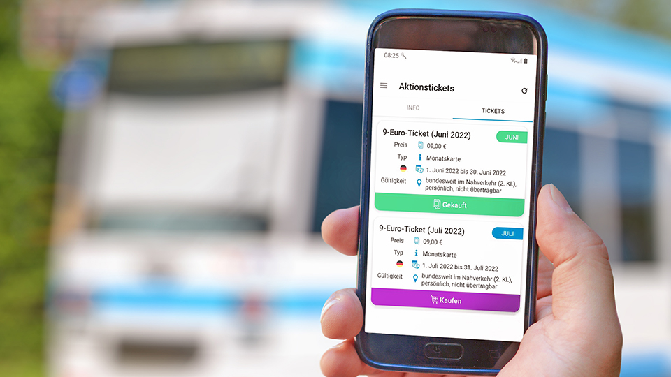 9-Euro-Ticket wird auf dem Handy angezeigt, im Hintergrund ein öffentliches Verkehrsmittel.