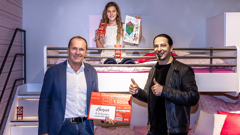 XXXLutz spendet für Bülent Ceylan-Stiftung: CEO von XXXLutz mit Bülent Ceylan und der Gewinnerin des Malwettbewerbs.