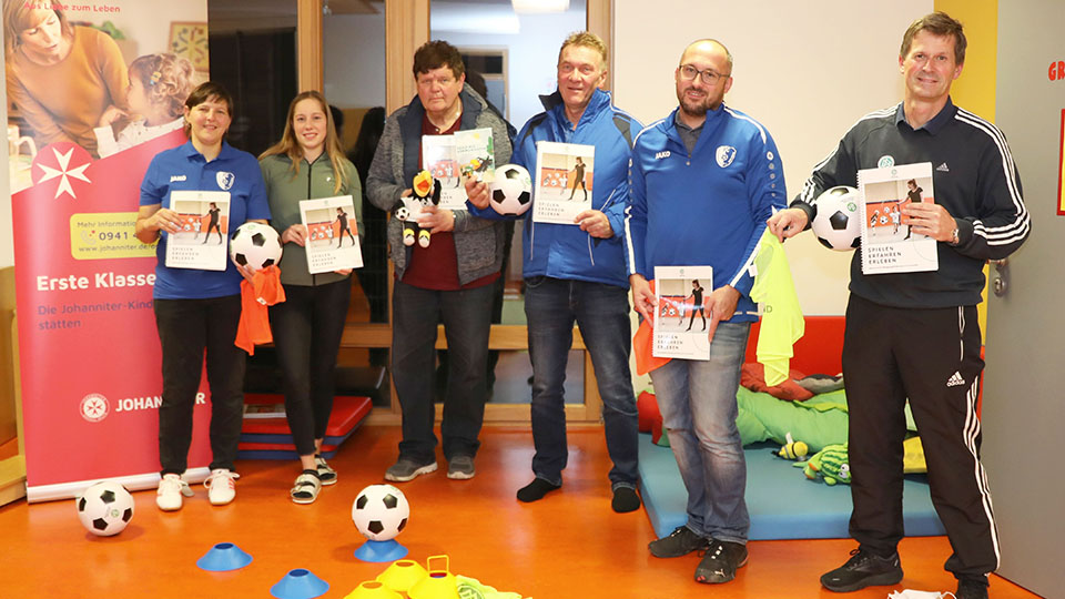 Johanniter-Kinderkrippe „Nesthäkchen" bekommt Fußballausrüstung. Verantwortliche und Mitarbeiter mit neuem Material in den Händen.