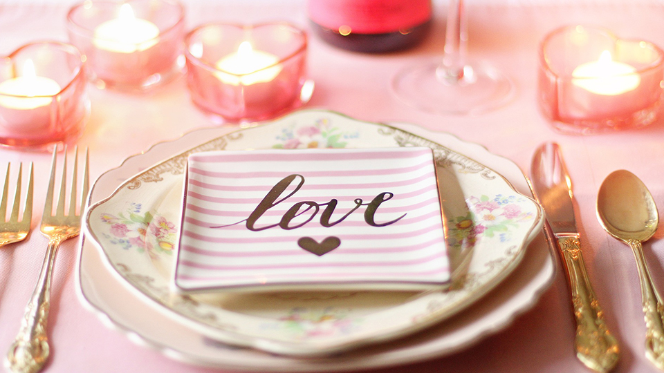 Tischdekoration in hellen rosa und goldenen Tönen mit Kerzen.