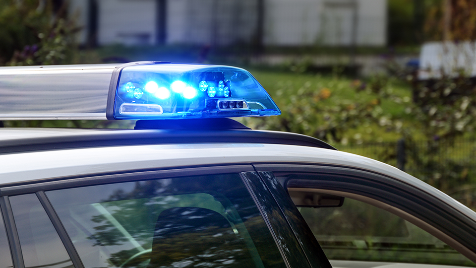 Blaulicht eines Streifenwagens der Polizei, der in einer Straße parkt.