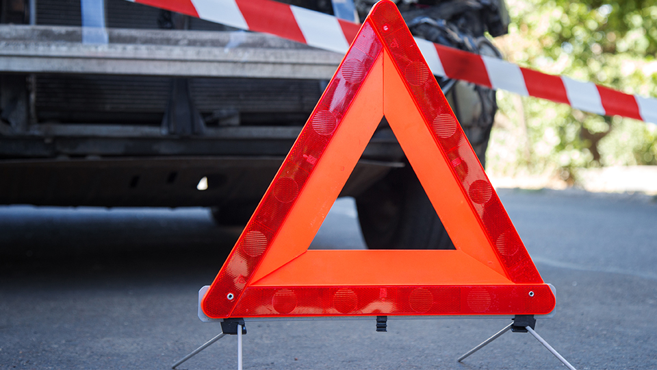 Warndreieck und Absperrungsband nach Verkehrsunfall