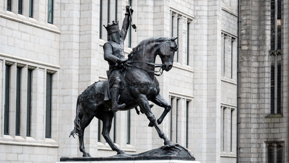 ABERDEEN, SCOTLAND - AUGUST 11, 2019: Black statue of Robert the Bruce, King of Scots in the centre of Aberdeen, Scotland in front of the Marischal College