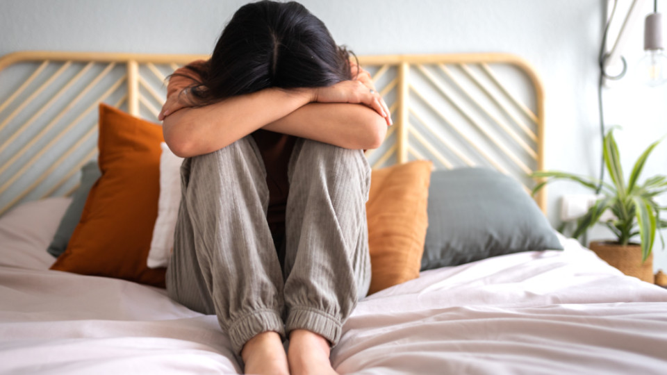 "Hilfe, mein Kind pubertiert": Jugendliche, die mit dem Gesicht in die Hände gelegt auf dem Bett sitzt.