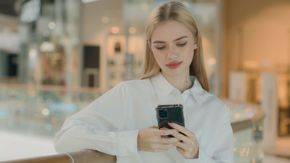 Junge blonde Frau lädt gerade eine App auf dem Handy