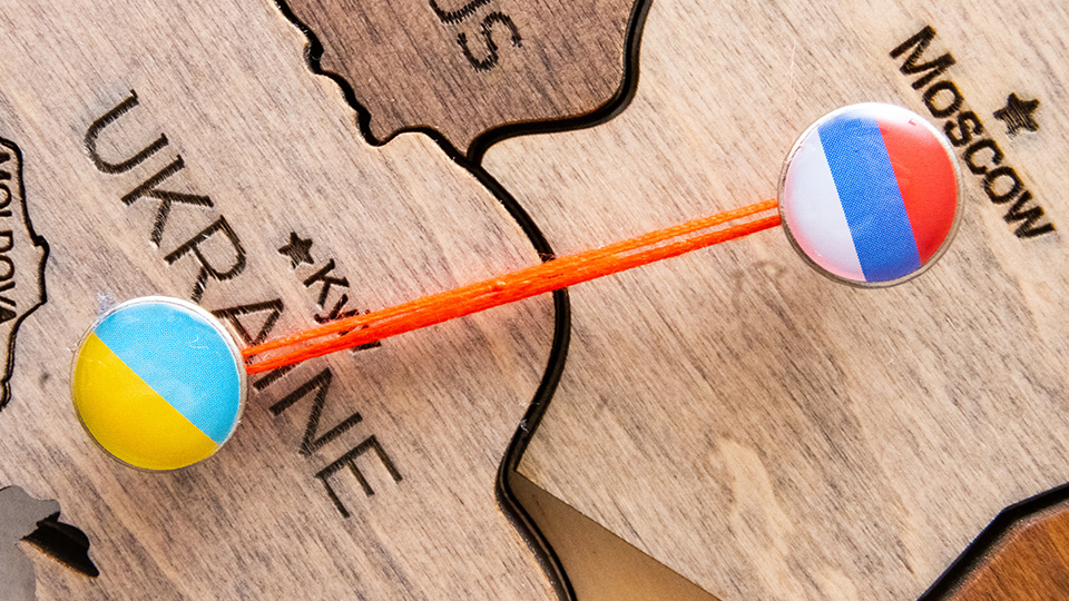 Hölzerne Landkarte, auf der eine rote Verbindung zwischen der Ukraine und Russland gezogen ist.