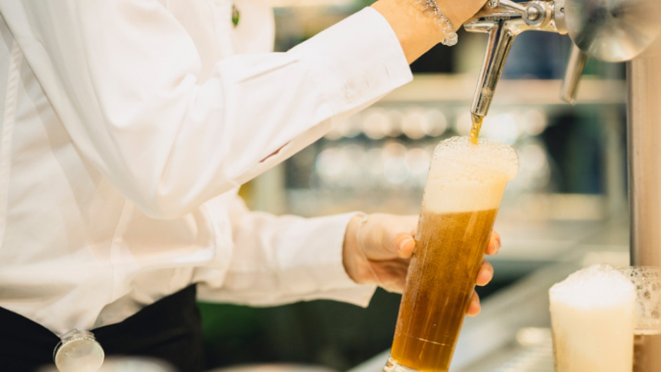 Beschäftigte, die gerade Bier an Zapfsäule ausschenkt