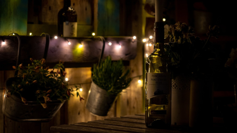 LED-Beleuchtung im Garten: Schöner Balkon mit verschiedenen Lichtern und einer Weinflasche