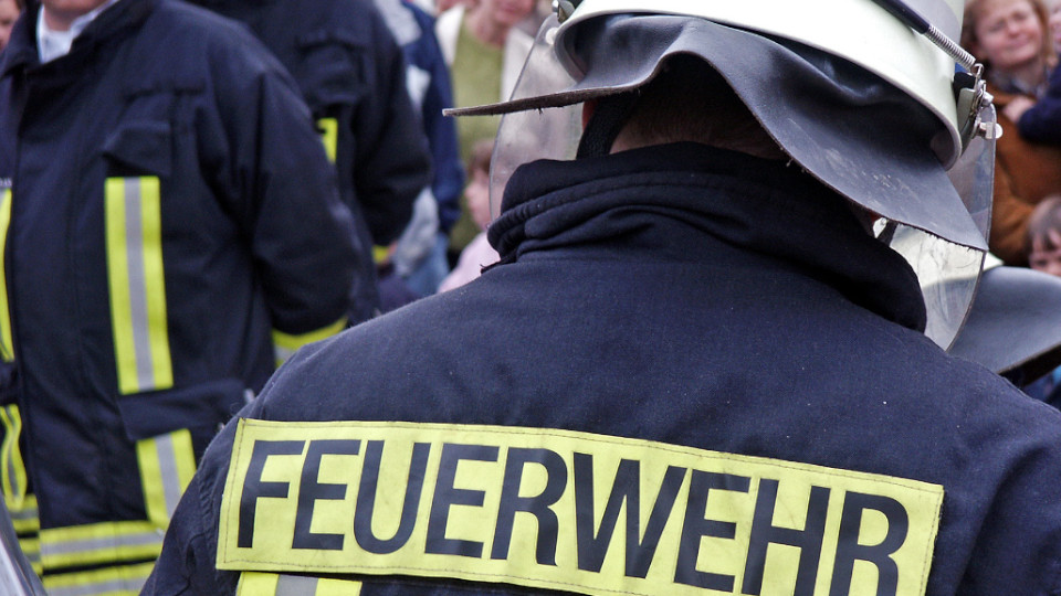 Wohnungsbrand in Regensburg: Feuerwehrmann mit Ausrüstung von hinten gemeinsam mit anderen Einsatzkräften