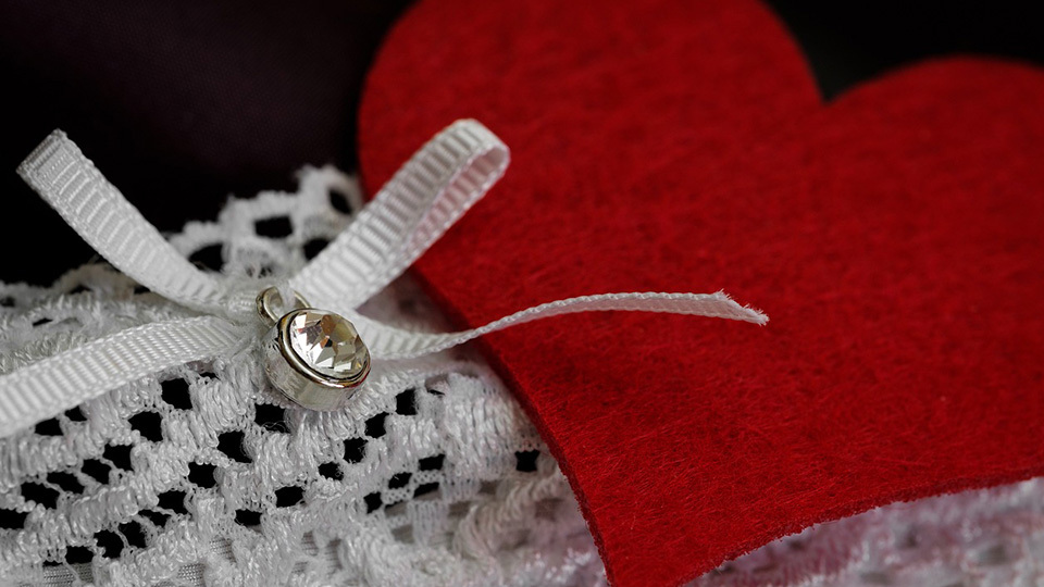 Ein Herz und daneben eine Schleife an einem gehäckelten weißen Kleidungsstück