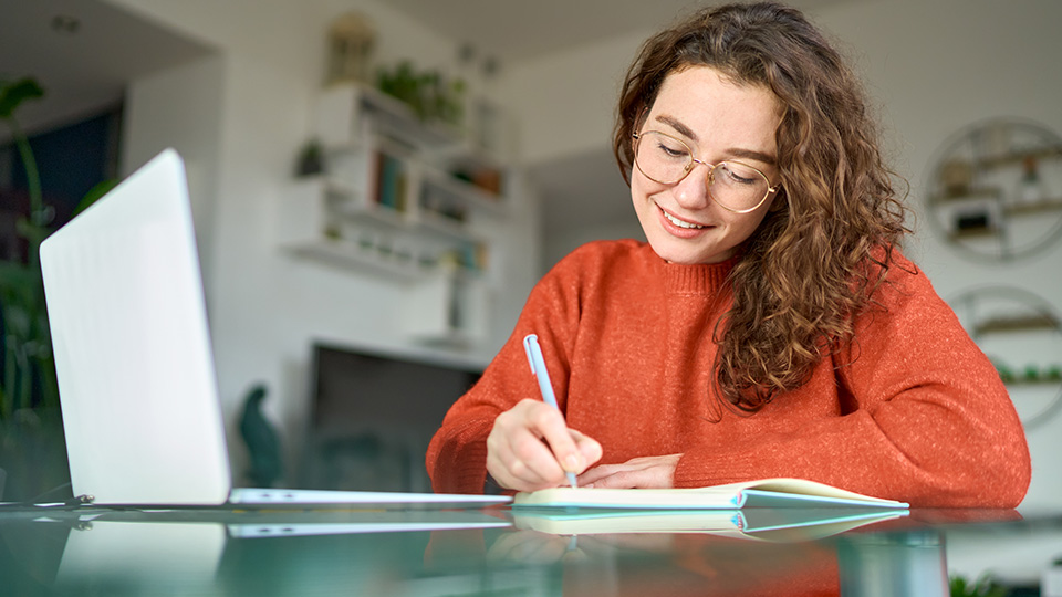 Frau, die gerade vor ihrem Laptop sitzt und einen Kurs absolviert
