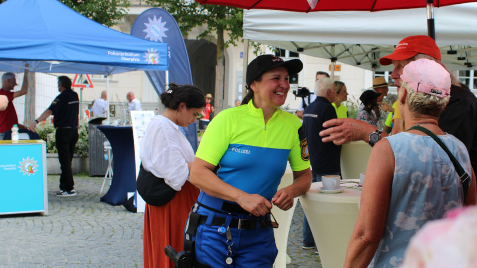 Coffee with a Cop am Bismarckplatz in Regensburg: Polizistin unterhält sich im Vordergrund mit interessierten Bürgern