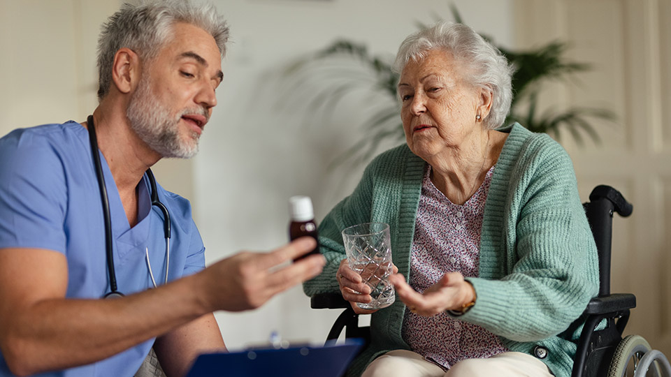 Pflegeberufe attraktiver machen: Männliche Pflegekraft informiert eine ältere Damen über ein Medikament