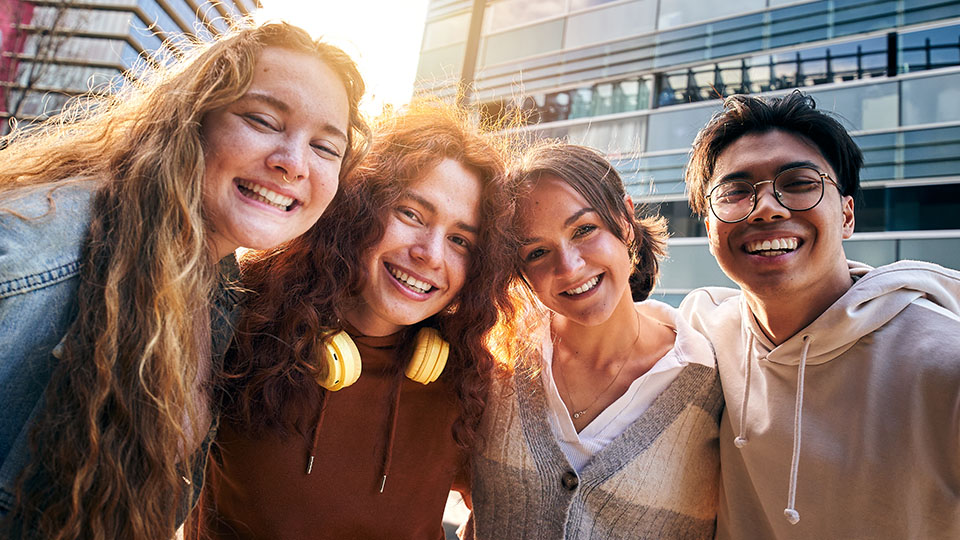 Vier internationale Schülerinnen und Schüler, die in die Kamera lächeln
