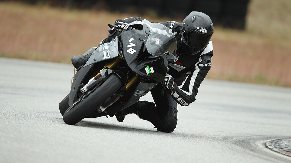 Motorradfahrerbekleidung: Mann auf Motorrad, der in dunkle Motorradkleidung gehüllt ist