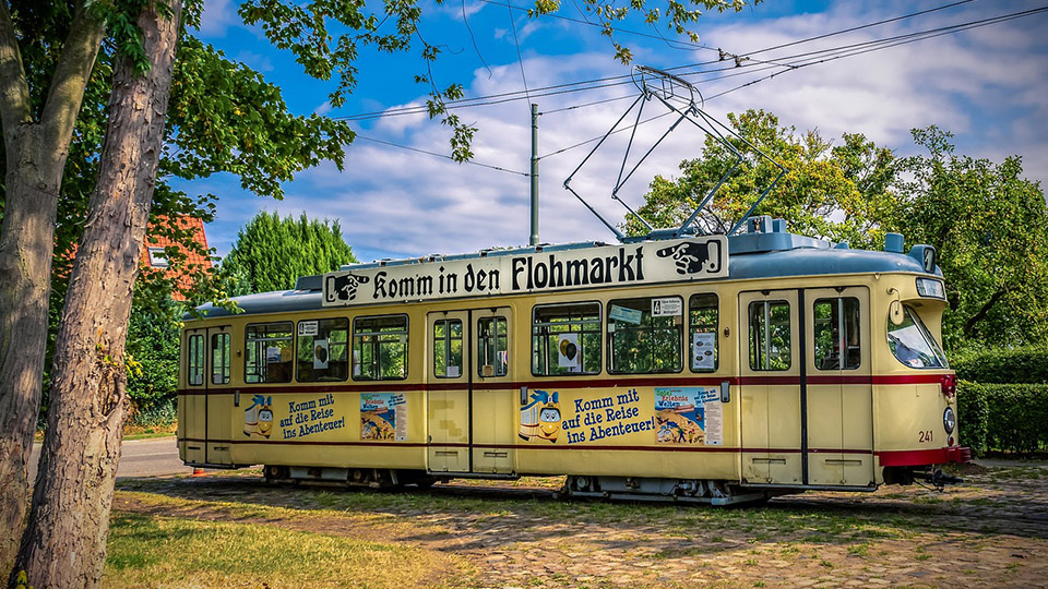 Alte gelbe Straßenbahn auf der der Schriftzug steht "Komm in den Flohmarkt"