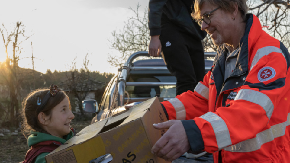 Ein Mitarbeiter der Johanniter uebergibt einem Kind ein Weihnachtspaket