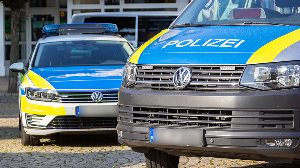 Zwei Streifenwägen der Polizei vor einem Gebäude