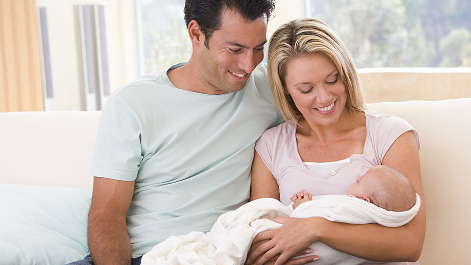 Frischgebackene Eltern auf der Couch mit ihrem Baby