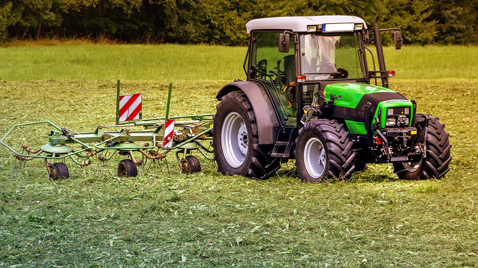 Landwirt auf seinem Traktor auf einer Wiese bei der Arbeit