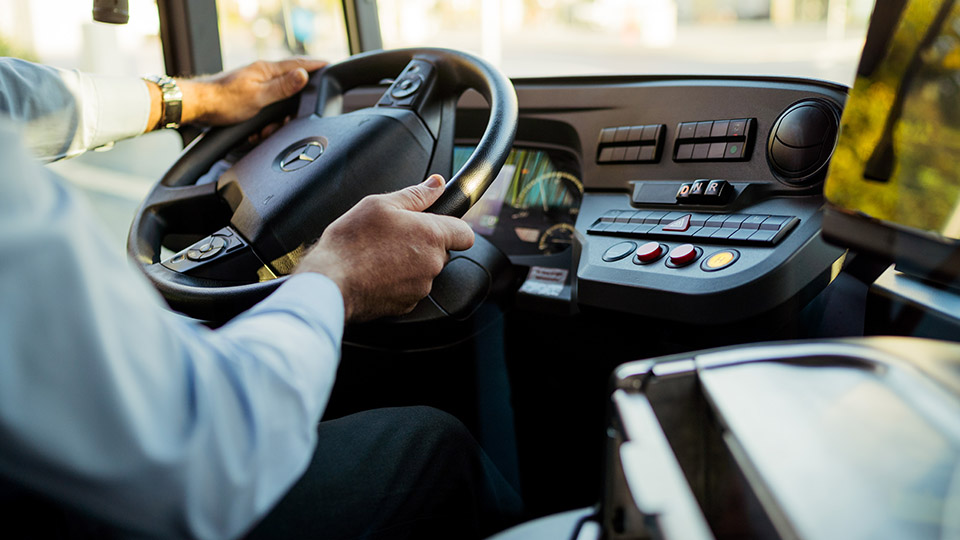 Busfahrer während der Fahrt: Nahaufnahme auf das Lenkrad und die Hände der Busfahrers