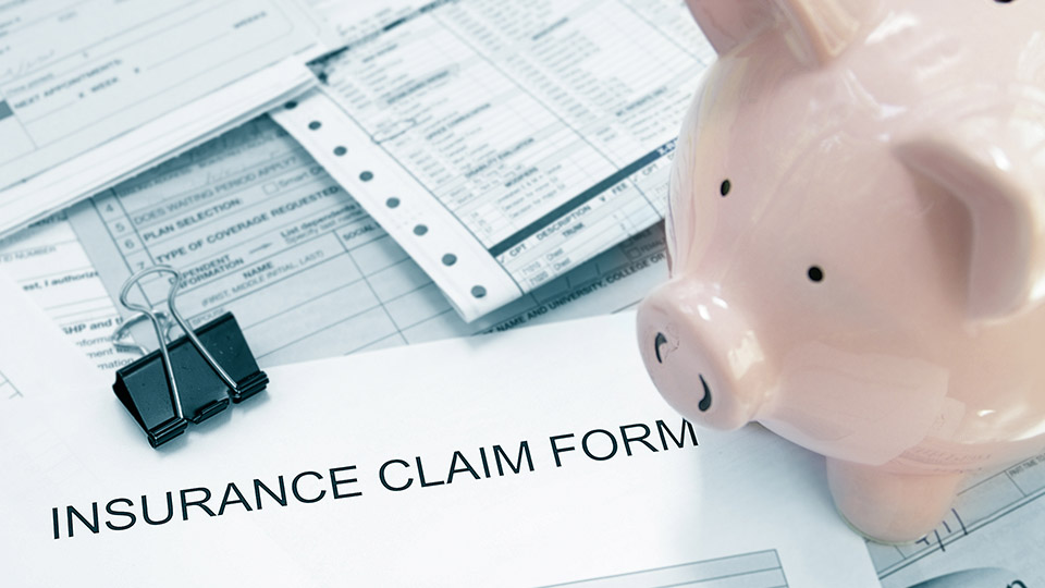 Antrag für eine Krankenversicherung auf Englisch (Stockfoto), daneben ein Sparschwein