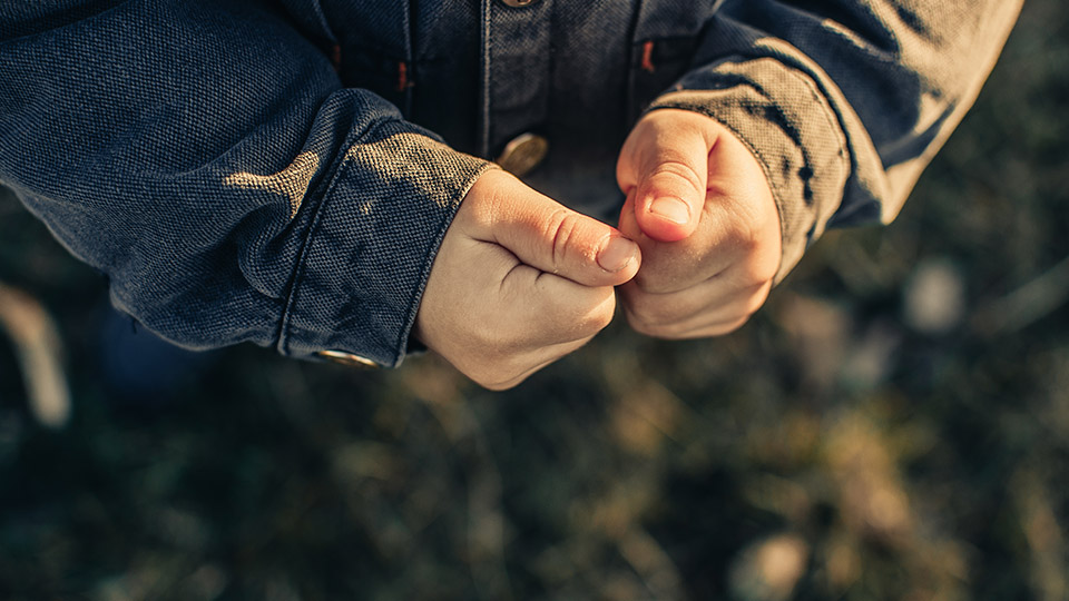 Hände eines Kindes vor dunklem Hintergrund