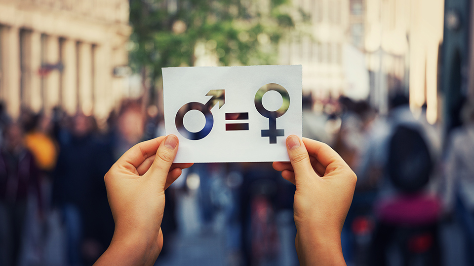 Internationaler Frauentag: Frau hält Zeichen in die Höhe, die die Gleichstellung von Mann und Frau darstellt.
