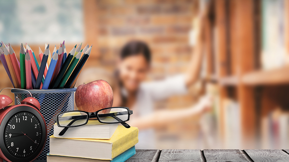 Lehramt Studium: Stiftebox, Wecker, Brille, Apfel und Bücher auf Schreibtisch