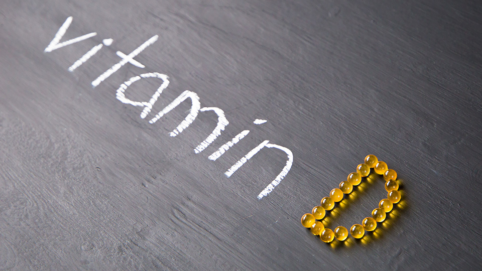 Vitamin D steht am Boden und formt sich aus Kreide und einzelnen Kapseln