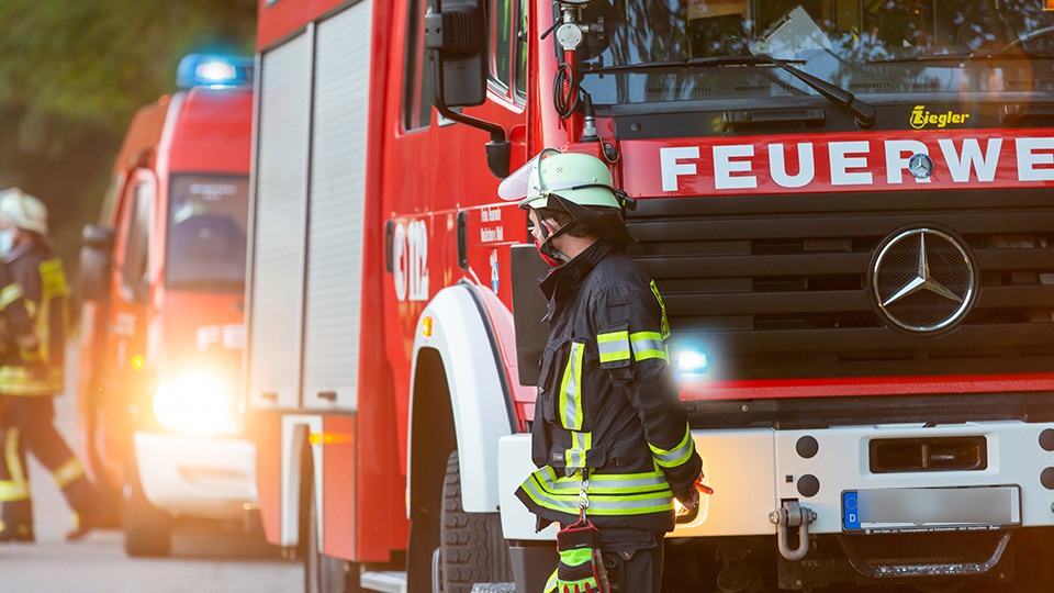Symbolbild: Feuerwehrkräfte vor Feuerwehrfahrzeug