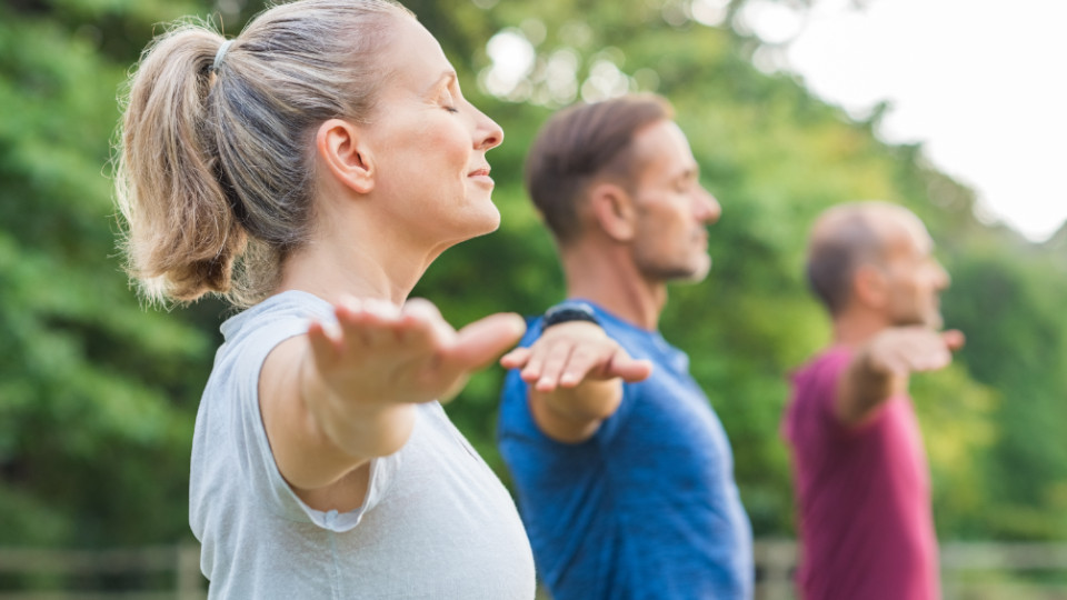 Yoga im Park: Eine Frau und zwei Männer während einer Übung