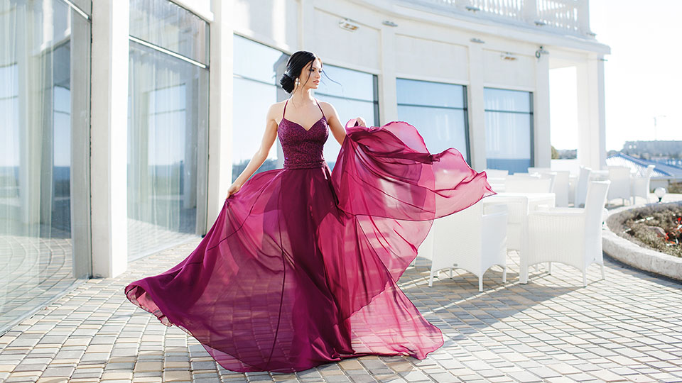 Frau in elegantem Abendkleid vor weißer Fassade