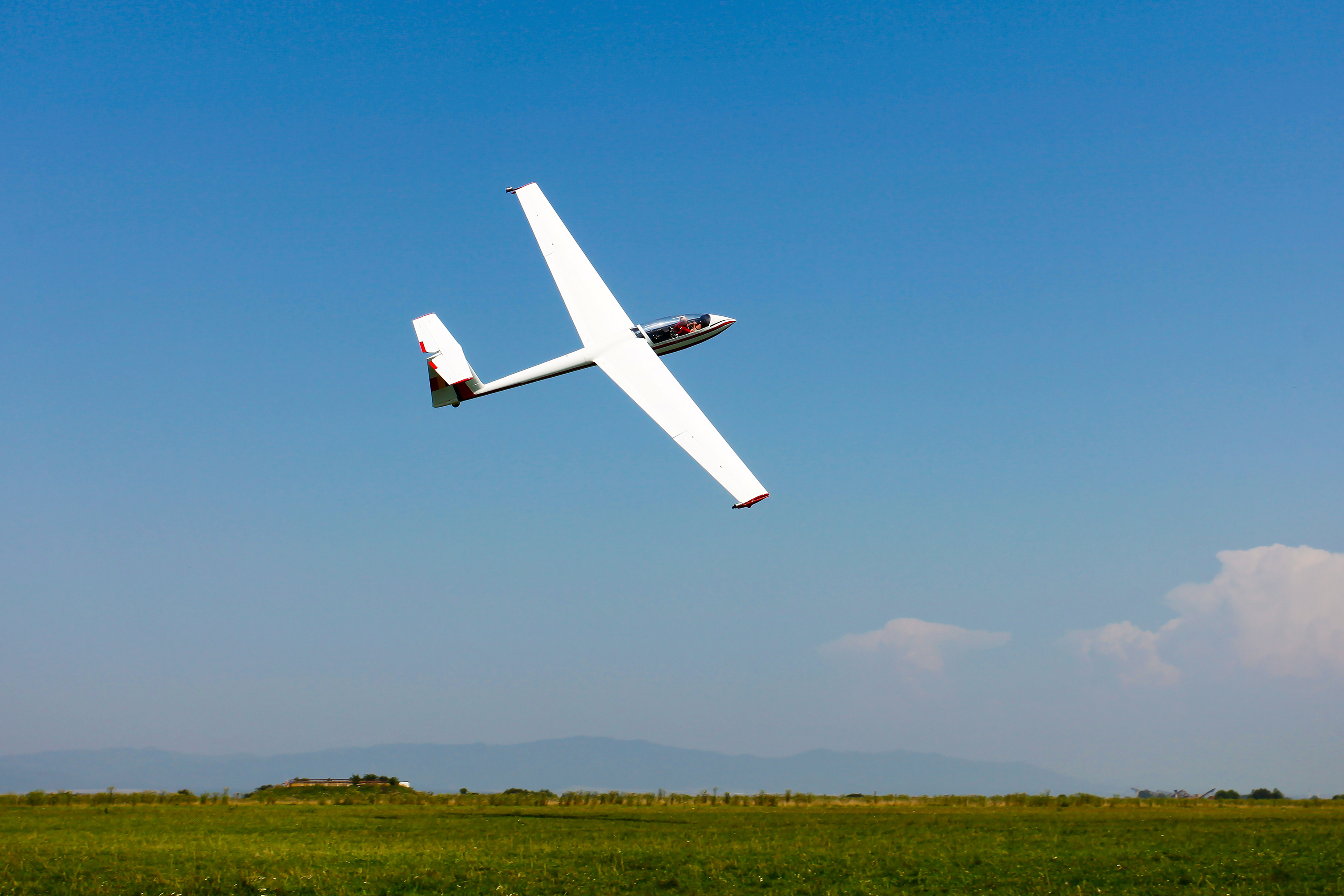 White glider flying on a blue sky