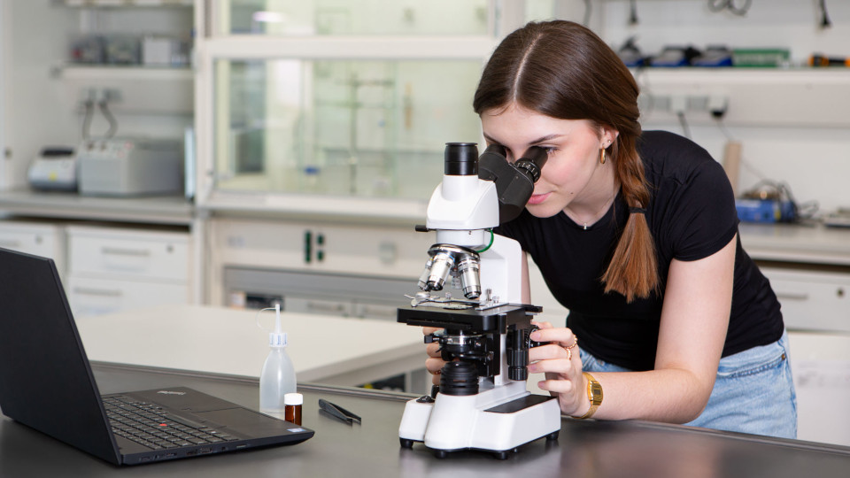 Mädchen blickt durch ein Mikroskop