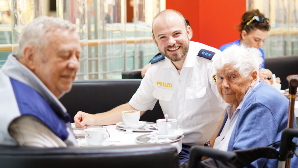 Polizist sitzt beim Kaffee trinken mit einer älteren Dame im DEZ, Regensburg