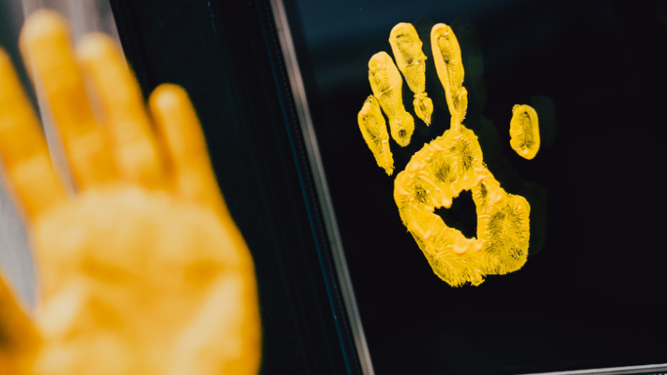 Eine gelbe Hand an einer Fensterscheibe