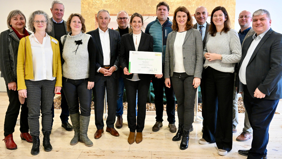 Dr. Ophelia Nick, Parlamentarische Staatssekretärin im Bundesministerium für Ernährung und Landwirtschaft (BMEL), überreichte das Dokument im Beisein zahlreicher Projektpartner und engagierter Akteure aus der Region: v.l.: Maria Politzka (LRA-Regensburg), Gudrun Schmidbauer (BSZ), Dr. Klaus Wiesinger (LfL), Anne Wurzbacher (AELF), Bürgermeister Ludwig Artinger, Robert Troidl (BSZ), Elke Oelkers (Biostadt und ÖMR) , Julius Kuschel (ÖMR), Landrätin Tanja Schweiger, Jürgen Mistol (MdL), Parlamentarische Staatssekretärin Dr. Ophelia Nick, Matthias Boßle (Johanniter Menüservice) sowie Stefan Schmidt (MdB)