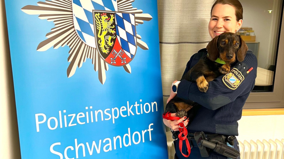 Polizisten hält Dackel auf dem Arm