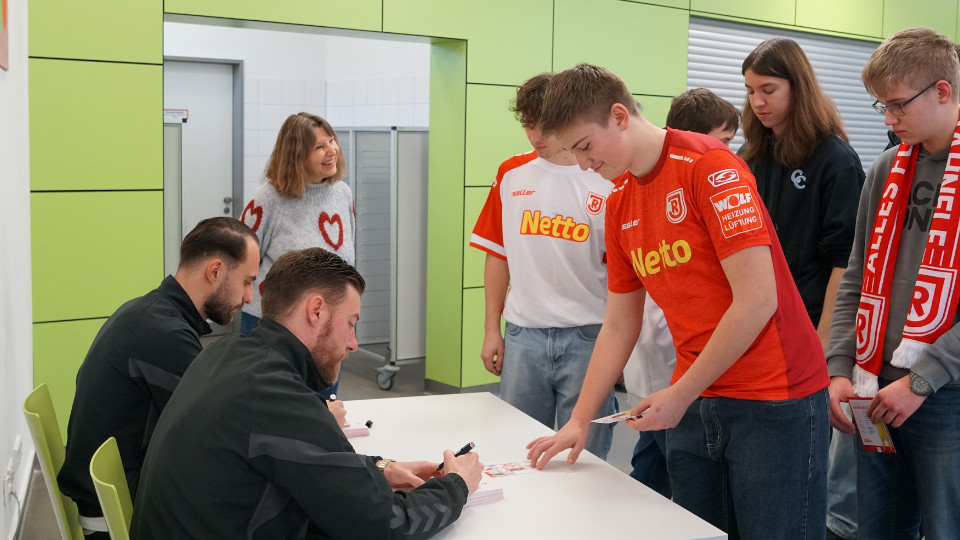 Schüler stehen vor Fußballern