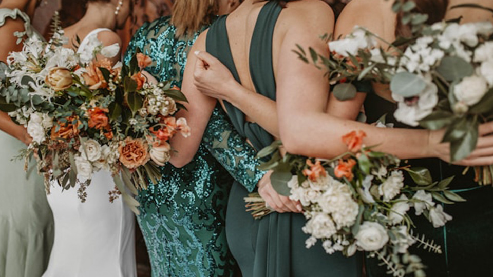 Hochzeitsgäste in schönen Kleidern stehen Arm in Arm