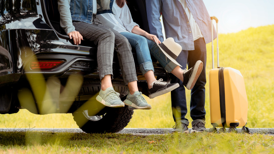 Familie sitzt im Kofferraum und lässt die Füße baumeln