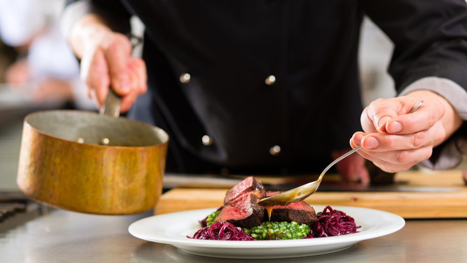 Symbolbild: Koch gibt Soße zu Gericht hinzu