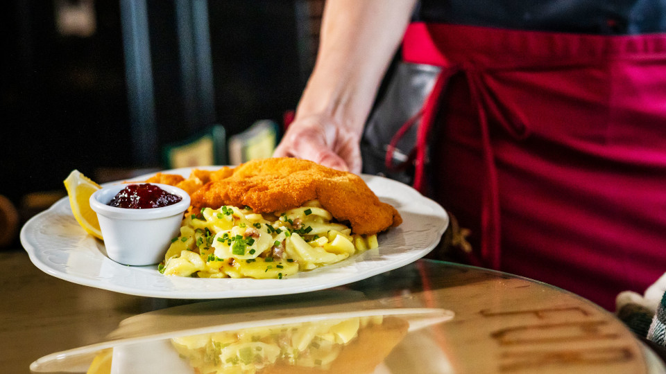 Kellnerin bringt Schnitzel Teller zum Tisch