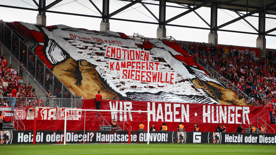 Fans halten Plakate beim Spiel hoch