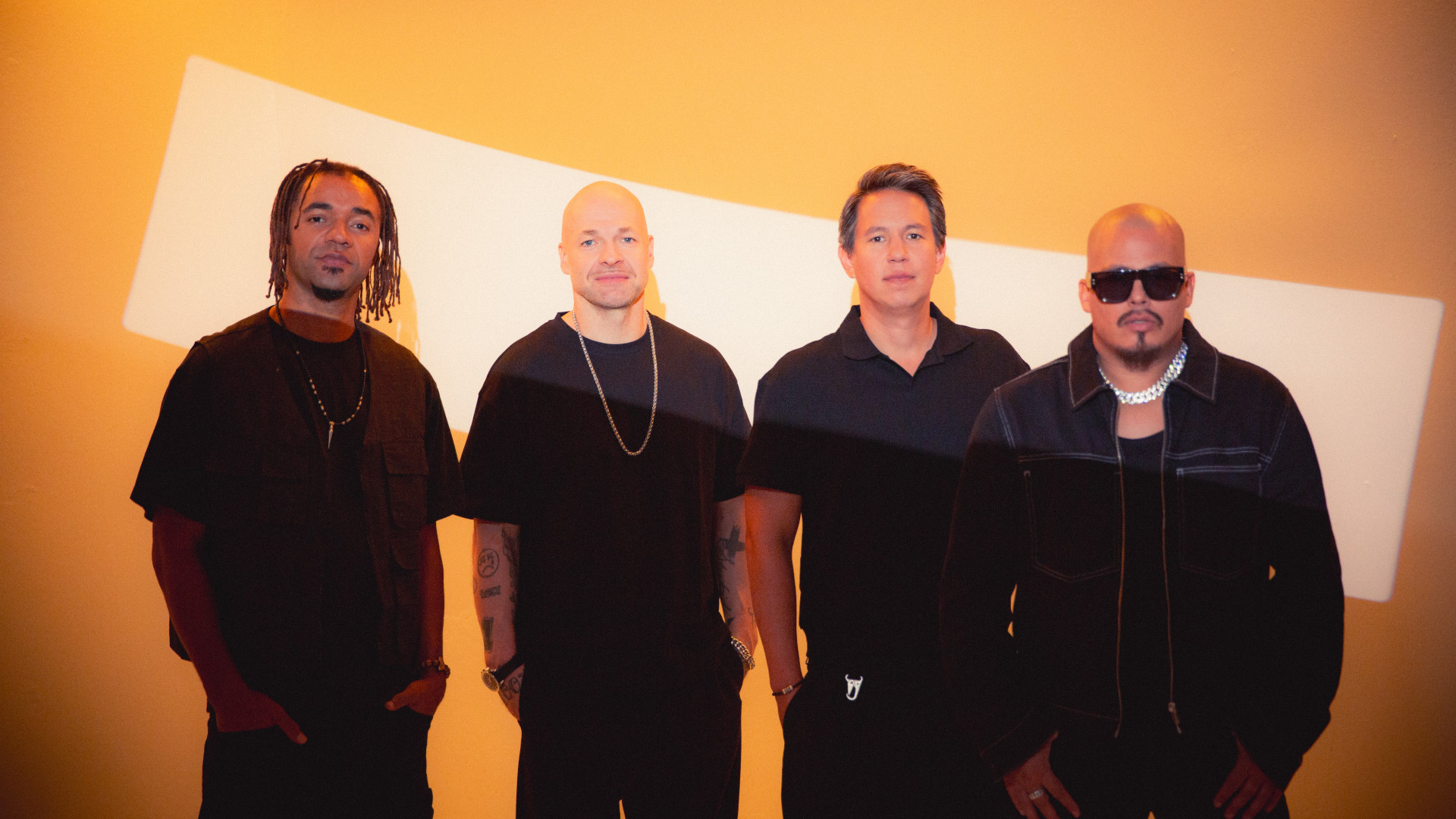 Culcha Candela steht vor einem orangefarbenen Hintergrund