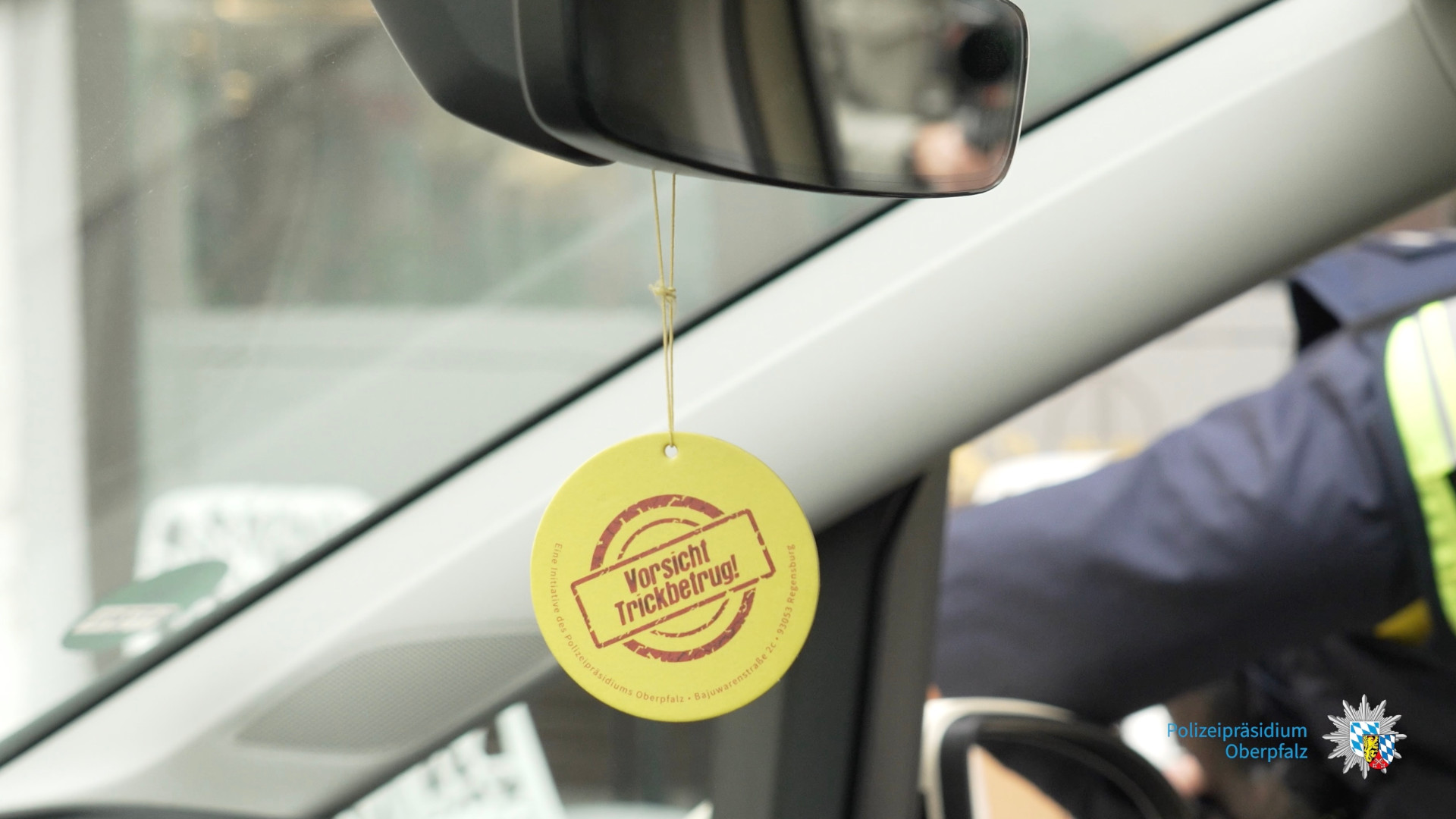 Duftbaum hängt im Auto mit der Aufschrift: "Vorsicht Trickbetrüger!"