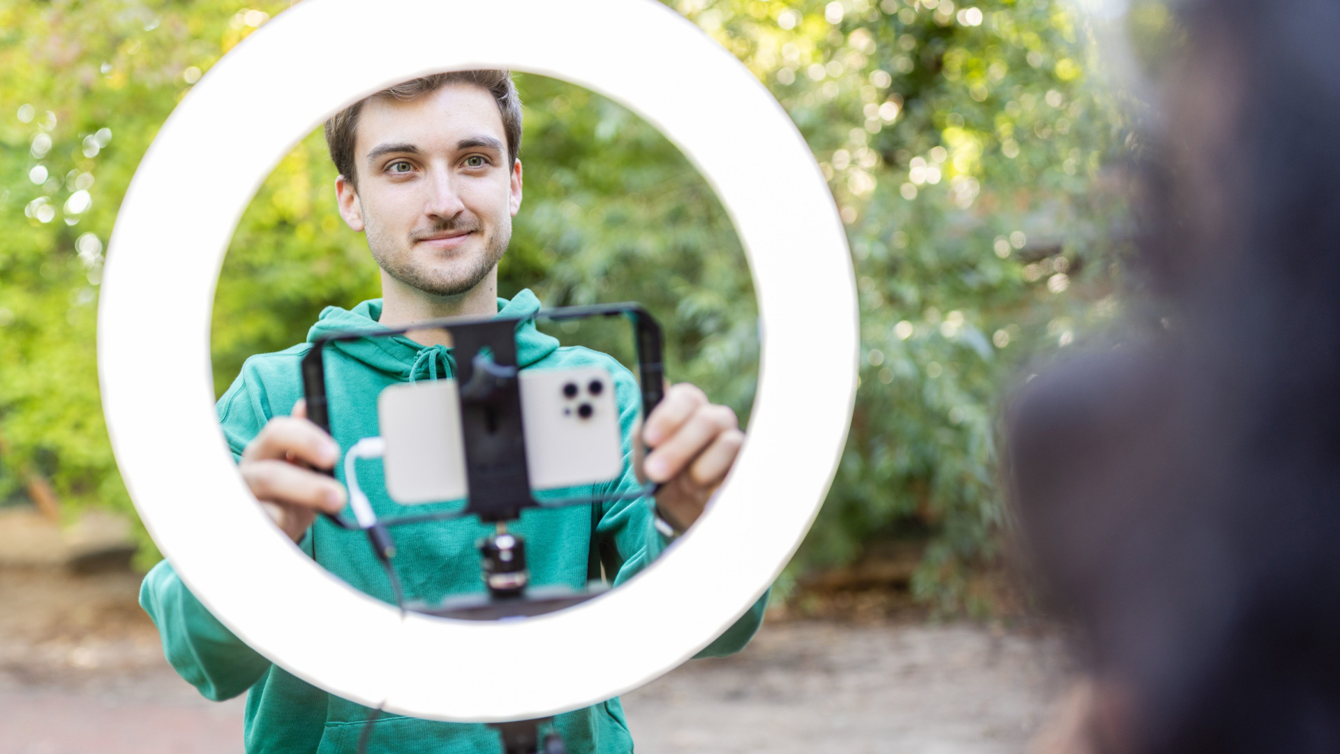 Schüler steht hinter einem Ringlicht mit dem Handy