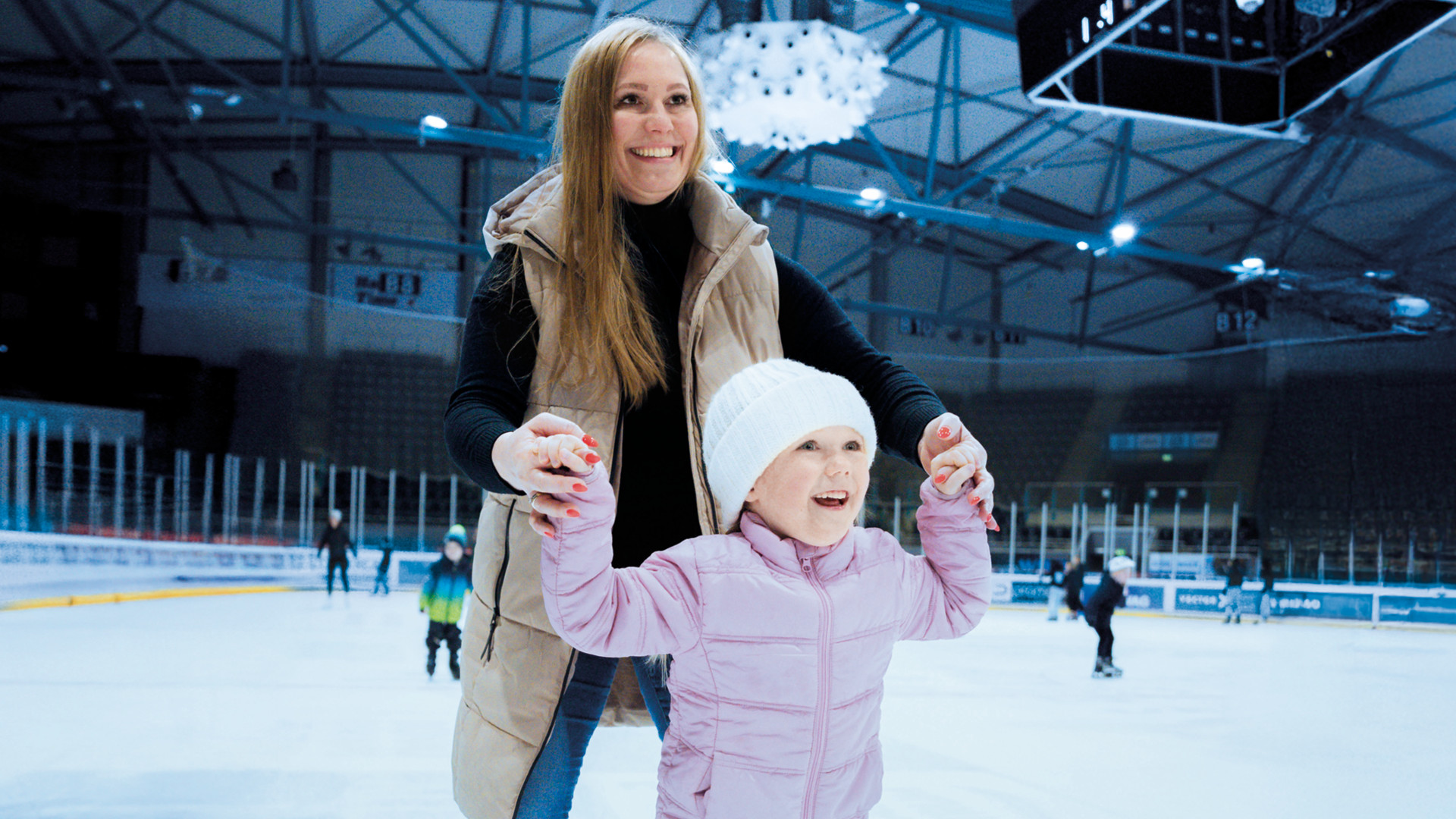 Frau fährt mit einem Kind an der Hand Schlittschuhe