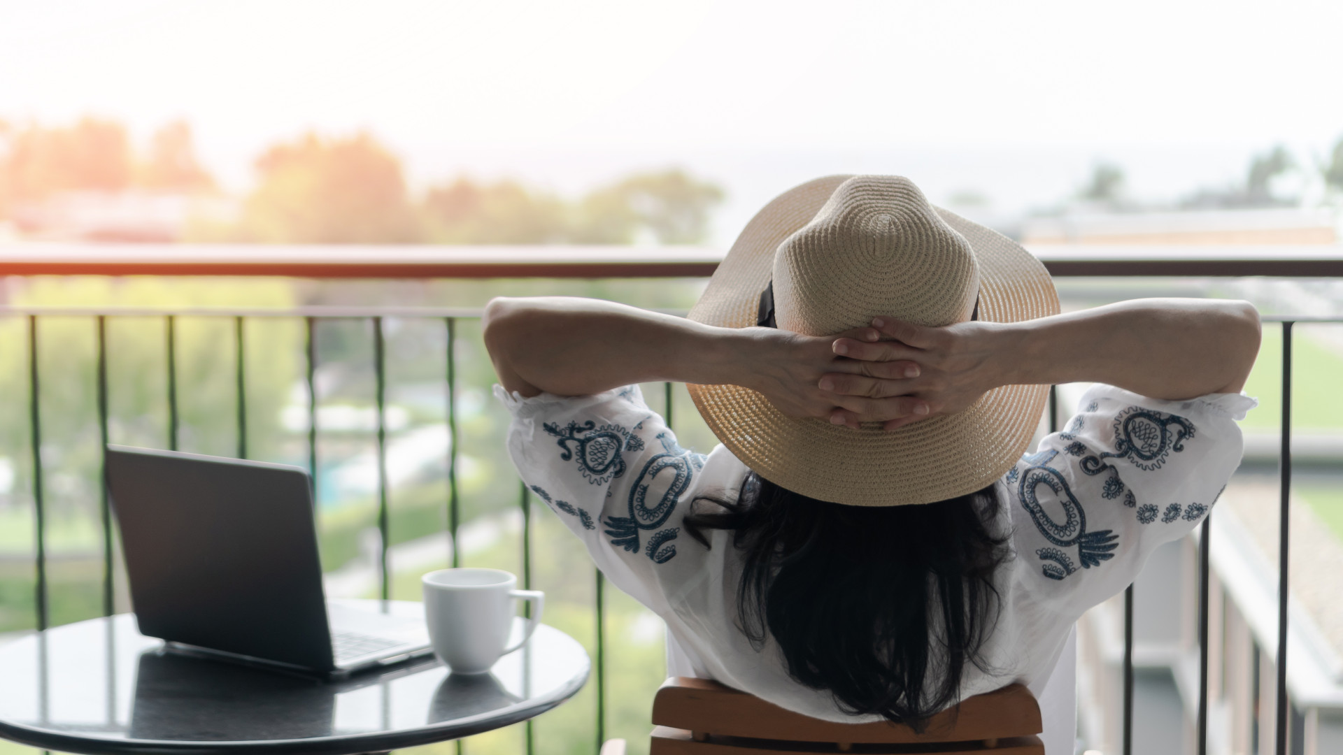 Symbolbild: Frau sitzt mit ihrem Laptop auf dem Balkon